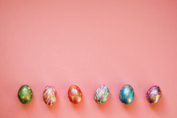 Colorful Easter eggs with golden foil on the pink background. Copy space.