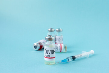 Covid-19 or coronavirus vaccination on blue background, ampoules of vaccine syringe on table, medical banner with copy space