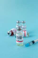 Covid-19 or coronavirus vaccination on blue background, ampoules of vaccine syringe on table, medical banner with copy space