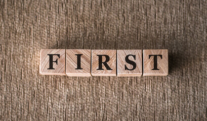 FIRST word written on wooden blocks on a brown backgroundю.