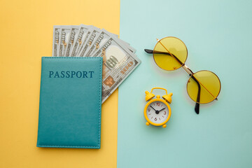 Time for journey. Alarm clock, sunglasses and passport with money banknotes on colorful background.