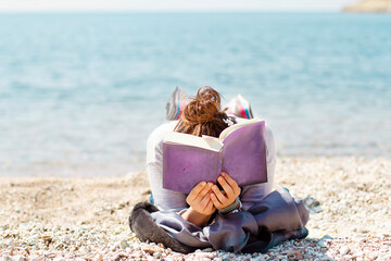 girl reading book  and sunbathing on the beach