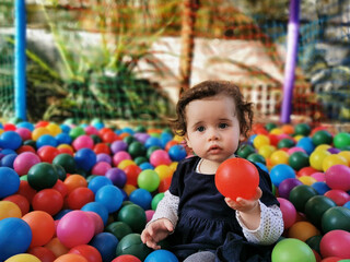 Fototapeta na wymiar Little baby playing alone in the ball pit