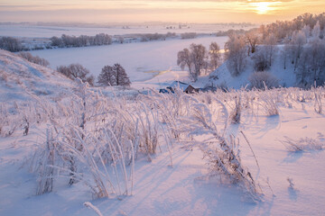 Beautiful winter landscape. Sunrise over the river. Snow-covered trees on the banks of the river.