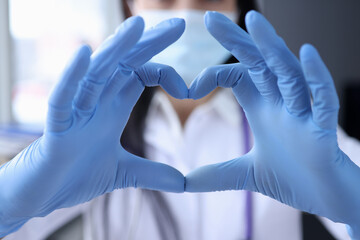 Hand of doctor in protective medical gloves is covering heart closeup