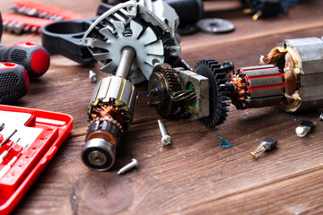 Power tool repair. Details of electrical appliance and repair tools on a wooden table in a repair...