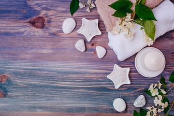Flat lay spa composition with jasmine flowers, sea salt in bowl, towels on wooden background