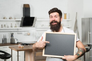 chalkboard for advertising. brutal hipster man holding blank board, copy space. job search. there are vacancies. shopping sale and discounts. chef menu in kitchen. look over there