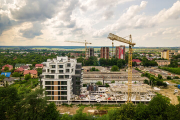 Fototapeta na wymiar Aerial view of tower lifting crane and concrete frame of tall apartment residential building under construction in a city. Urban development and real estate growth concept.