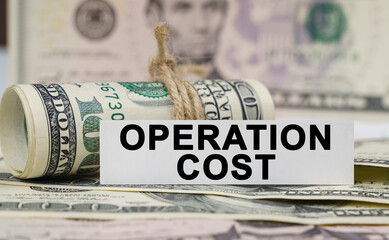 On the table are bills, a bundle of dollars and a sign on which it is written - OPERATION COST