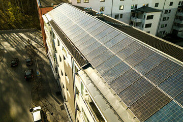 Fototapeta premium Aerial view of solar photovoltaic panels on a roof top of residential building block for producing clean electric energy. Autonomous housing concept.