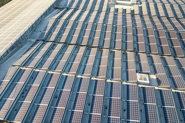 Aerial view of many photo voltaic solar panels mounted of industrial building roof.