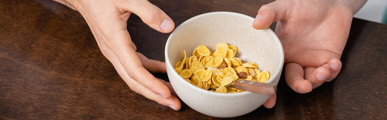 cropped view of homosexual men holding bowl with corn flakes, banner