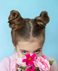 Naklejka premium Portrait. Girl 6-7 years old sniffing a bouquet of flowers and looking at the camera