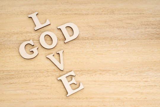 God is Love concept. Words forming a cross on wooden table