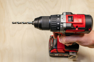 Installs the drill into the drill, hands take the drill and install it into the electric drill