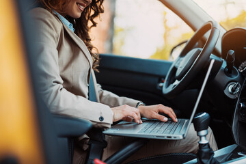 Fototapeta na wymiar Beautiful young businesswoman driving car and using laptop.