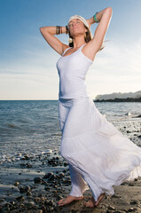 Fototapeta na wymiar attractive blonde woman dressed in white enjoying on the seashore