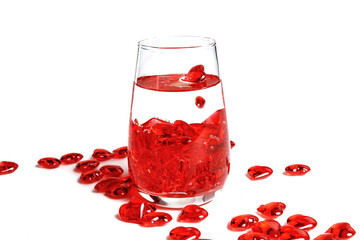 Valentine's Day. Small red glass hearts in a glass of water. A splash of liquid.