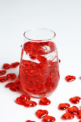 Valentine's Day. Small red glass hearts in a glass of water. A splash of liquid.