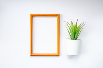 a brown, wooden frame with a green plant and space for text on a white background. Top view.