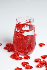 Valentine's Day. Small red glass hearts in a glass of water. A splash of liquid.