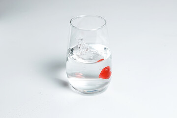 Valentine's Day. Small red glass hearts in a glass of water. A splash of liquid.