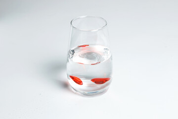 Valentine's Day. Small red glass hearts in a glass of water. A splash of liquid.