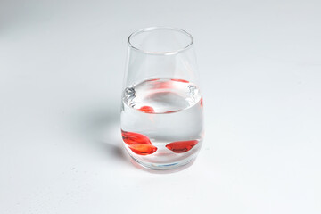 Valentine's Day. Small red glass hearts in a glass of water. A splash of liquid.