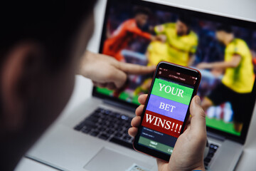 Man watching football online broadcast on his laptop and celebrate victory in betting at bookmaker's website. Betting and gambling concept.