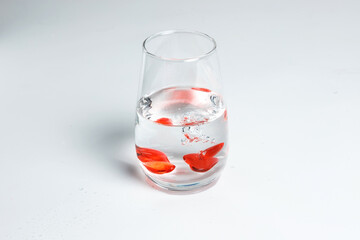 Valentine's Day. Small red glass hearts in a glass of water. A splash of liquid.