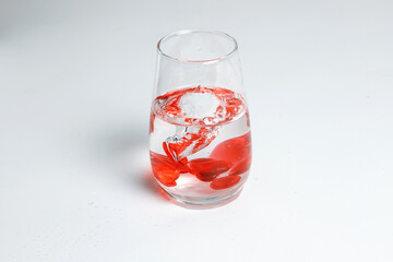 Valentine's Day. Small red glass hearts in a glass of water. A splash of liquid.
