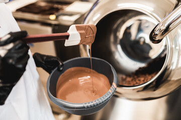 Professional confectioner making sweets wth melted chocolated in pastry shop. .