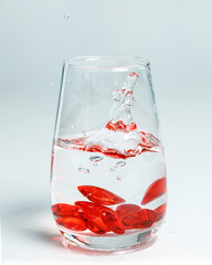 Valentine's Day. Small red glass hearts in a glass of water. A splash of liquid.
