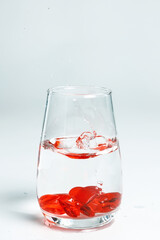 Valentine's Day. Small red glass hearts in a glass of water. A splash of liquid.