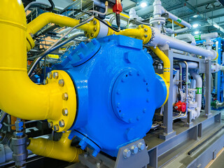 Gas processing station. Pumping equipment at the gas station. Blue-yellow pipes at a gas processing plant. Pump chemical plant from inside. Lots of pipes in a chemical plant. Chemical industry.