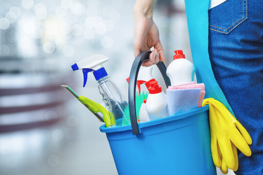 Cleaning lady holding a bucket of cleaning products in her hands .