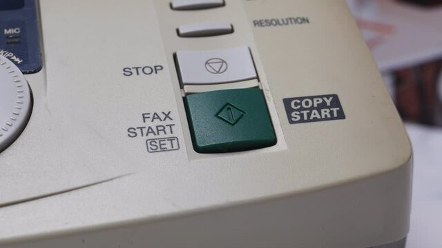 Male Finger Presses The Start Button On Old White Fax.