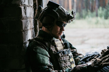 A thoughtful soldier, resting from a military operation while it is raining outside.