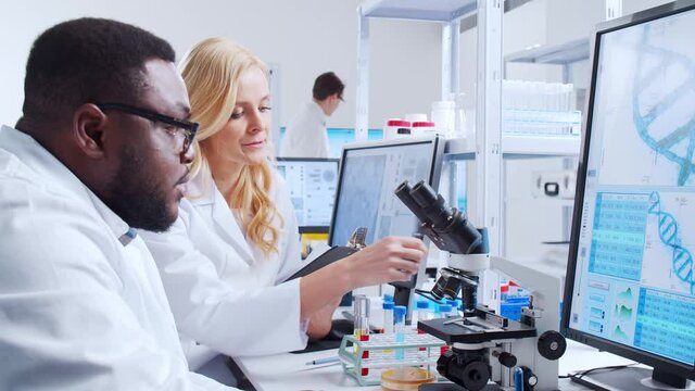 Professional team of scientists is working on a vaccine in a modern scientific research laboratory. Genetic engineer workplace. Futuristic technology and science concept.
