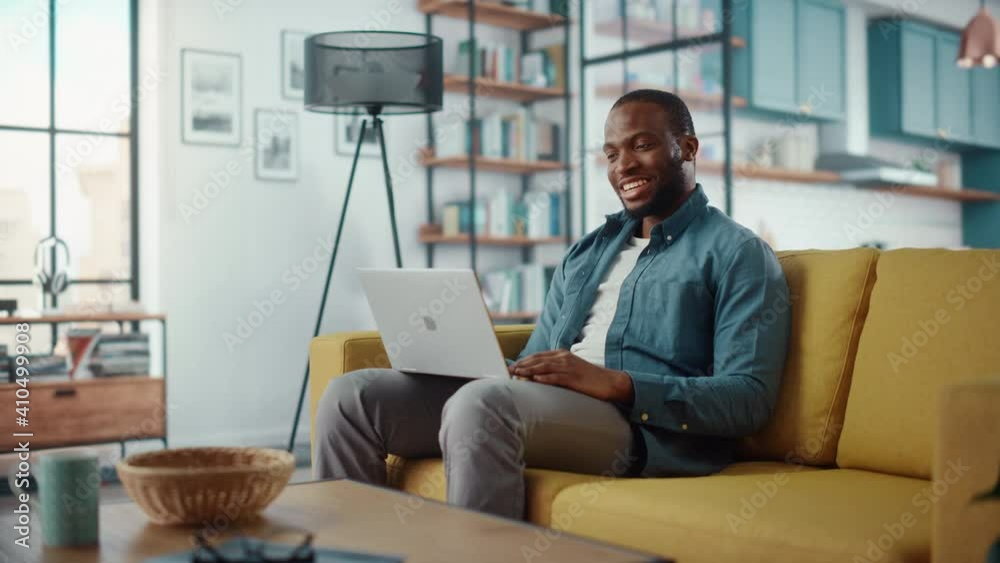 Poster handsome black african american man having a video call on laptop computer while sitting on a sofa i