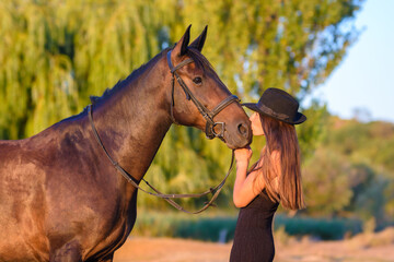 Obraz premium A girl kisses a horse in the rays of the setting sun