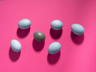 Blue easter hen eggs on dark pink background.