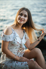 Blonde girl in summer light dress in summer outdoors