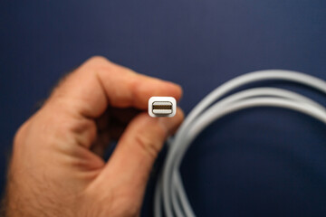 Man holding fast Thunderbolt 2 Cable 2 meter long manufactured in white plastic - isolated on blue...