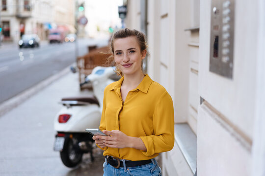 Young woman holding a mobile smiling at camera