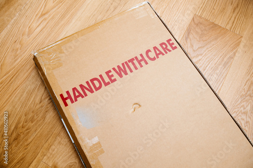 Handle With Care Inscription On The Cardboard Box Of A New Parcel Delivered By Freight Transportation Service Arranged On The Wooden Parquet Floor Wall Mural Ifeelstock