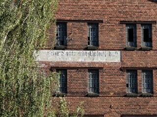 Altes verfallenes Backstein-Fabrikgebäude mit eingeschlagenem Fenster