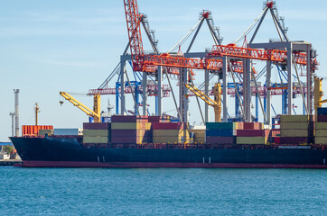 Port cargo crane loads a container onto a cargo ship in a seaport