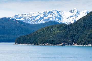 Snow-capped mountains and evergreen trees along the coast of southern Alaska